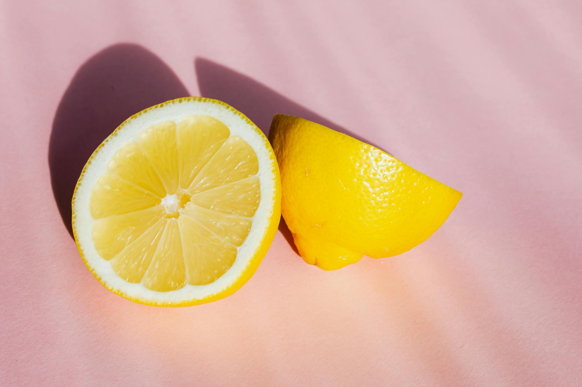 Fresh lemon halves on a pink background, symbolizing fresh starts and citrus-inspired vibrator design
