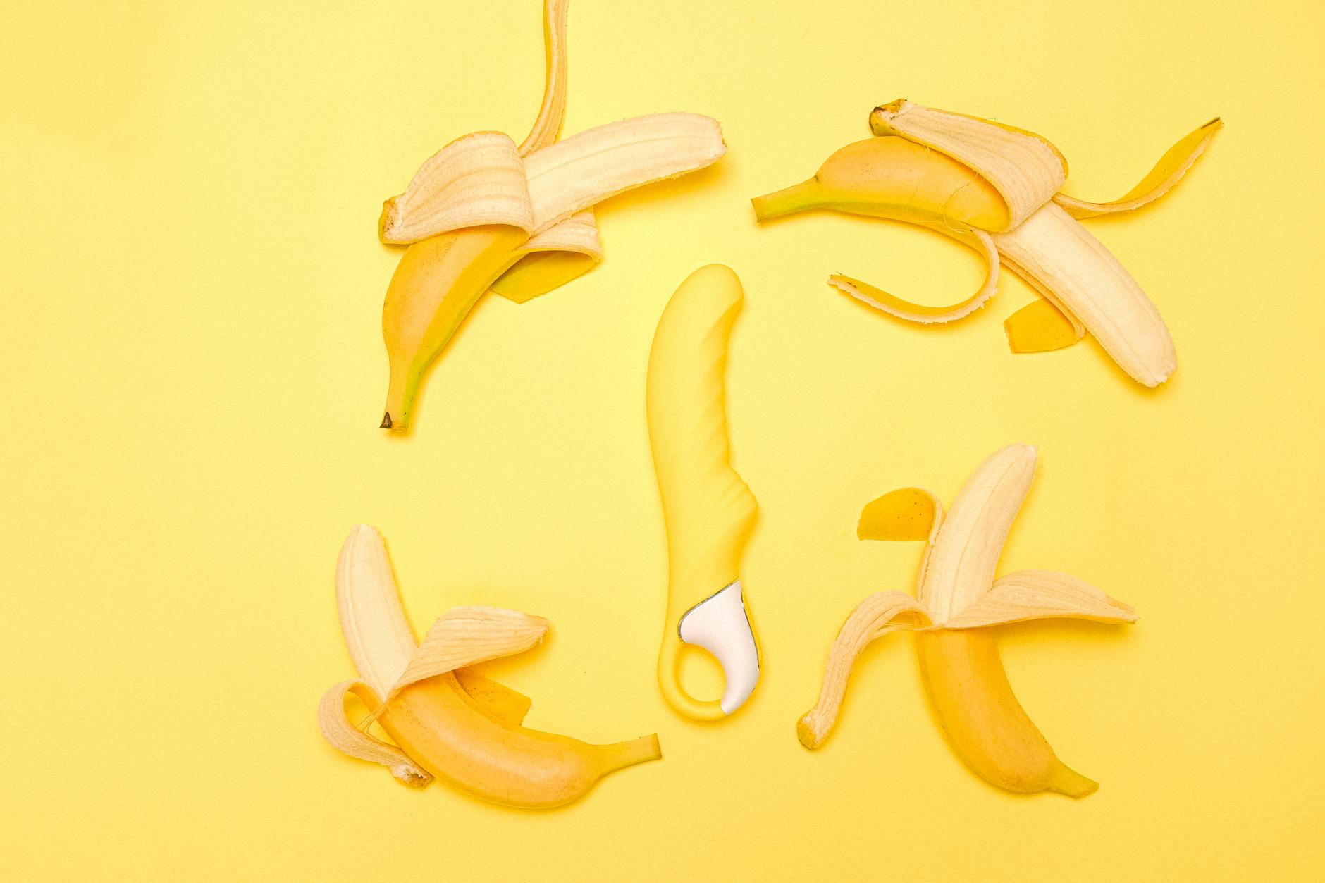 Yellow silicone lemon clitoral vibrator on a bright yellow background surrounded by fresh lemons