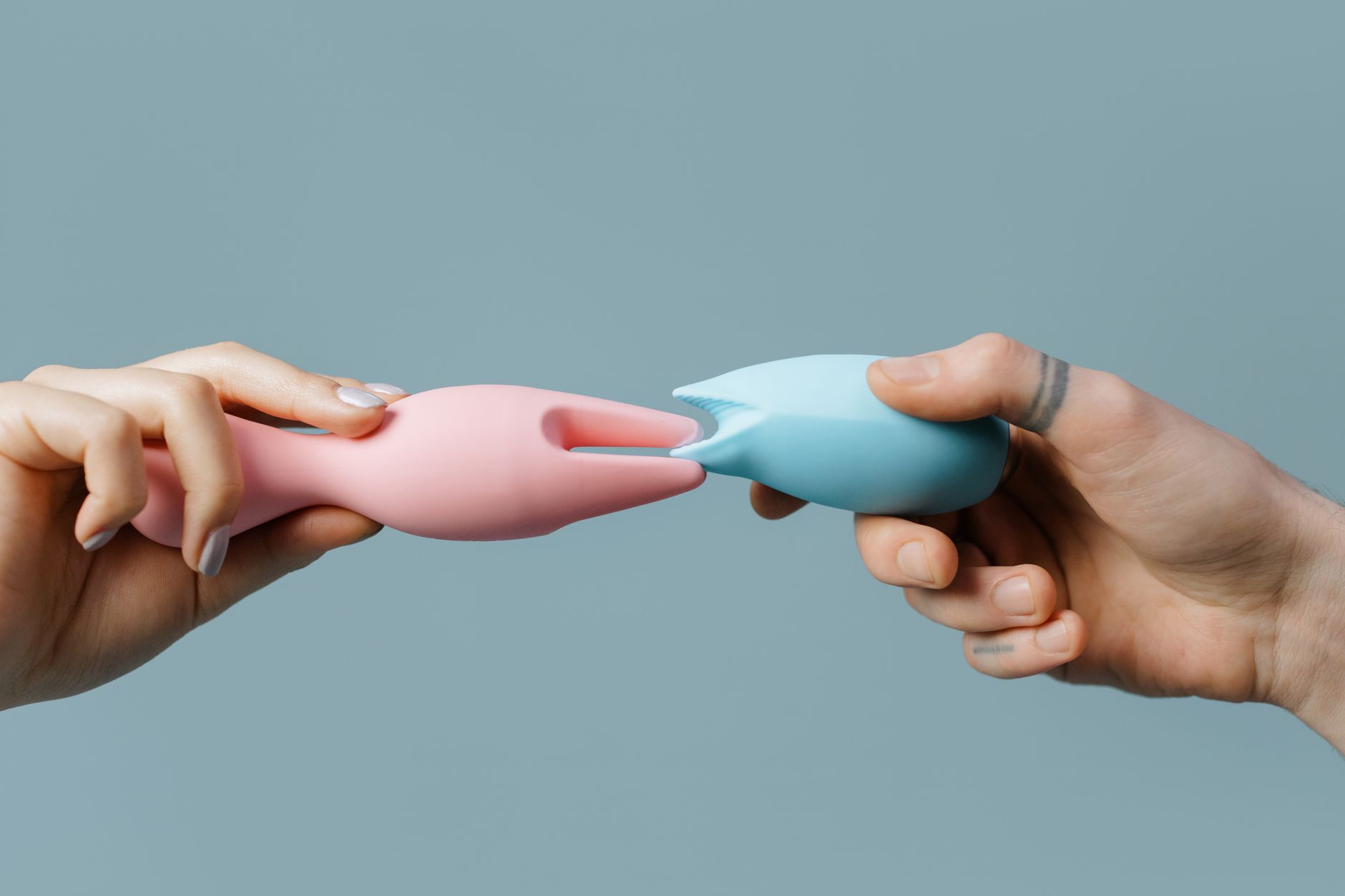 A couple standing together indoors, holding a blue vibrator and reconnecting intimately