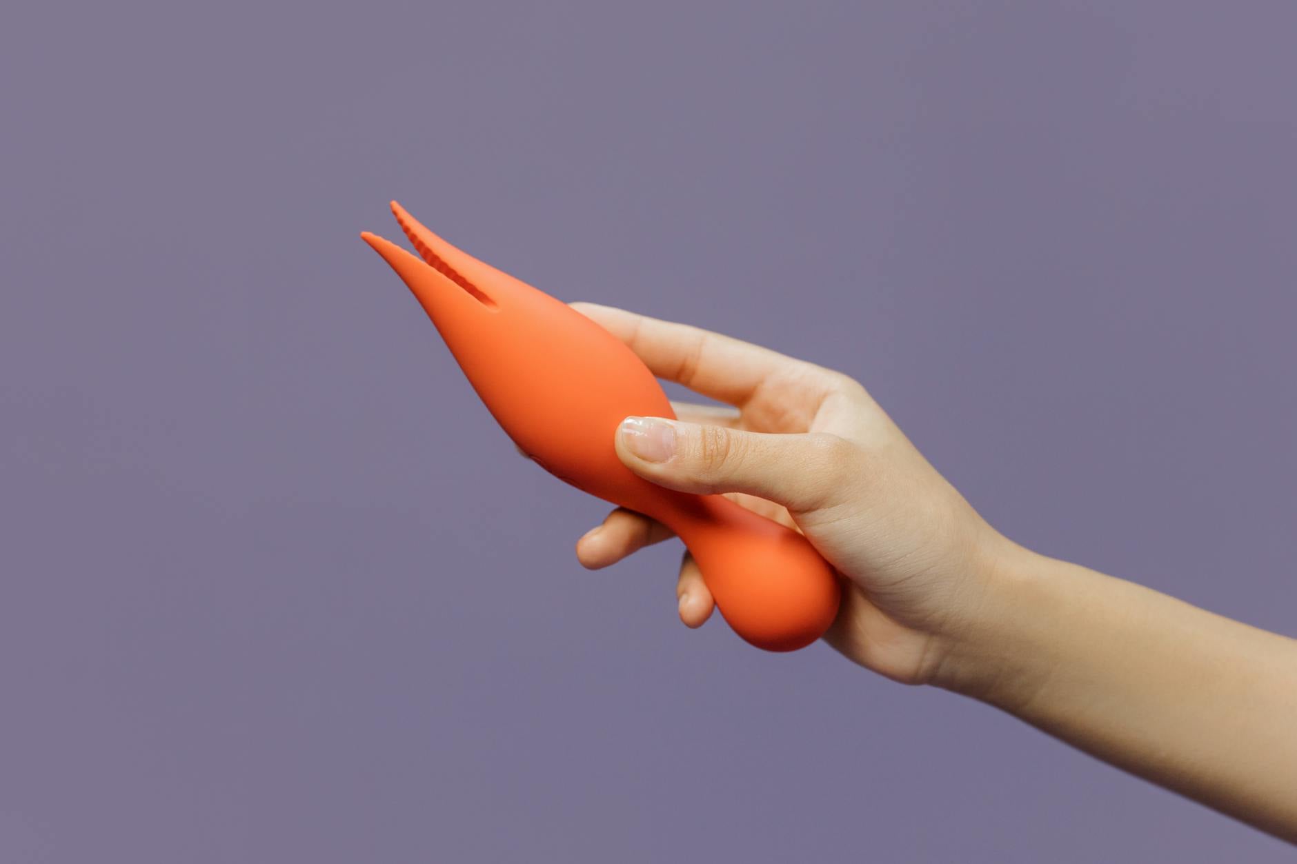 A hand holding a lemon vibrator against a minimalistic backdrop, showcasing solo pleasure and self-care