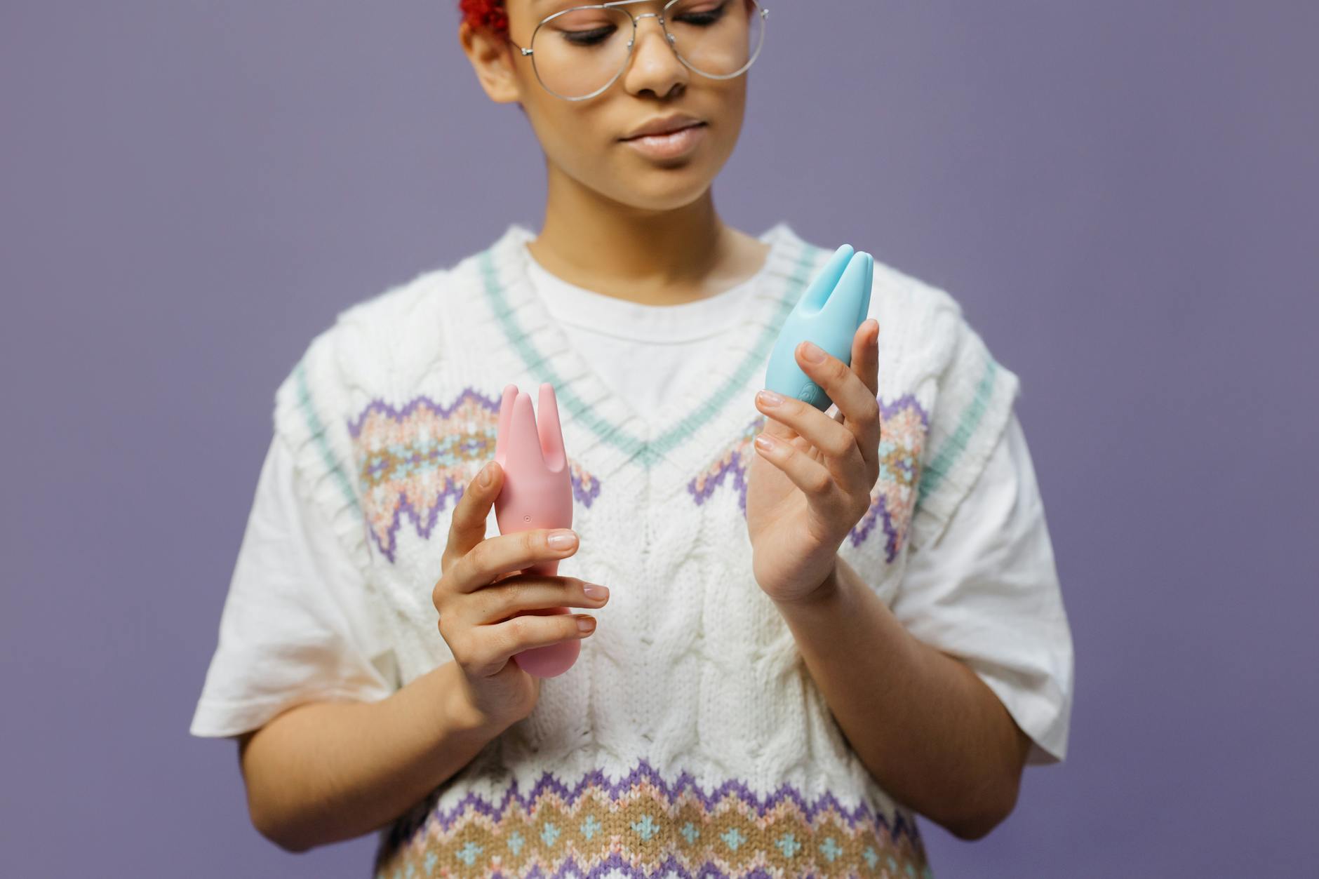 Woman holding clitoral vibrators in a thoughtful moment, considering how to use them comfortably